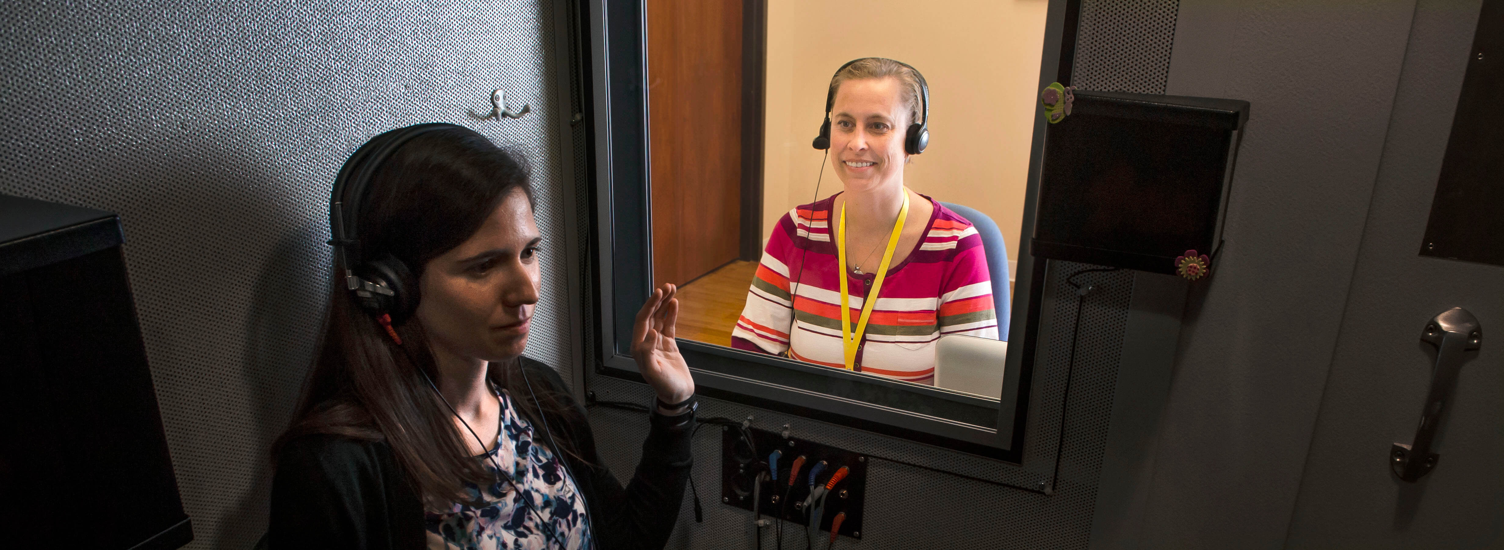 Laura Burger performs a hearing test on a patient in a soundproof booth