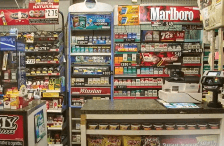 Convenience store counter with tobacco for sale behind it.